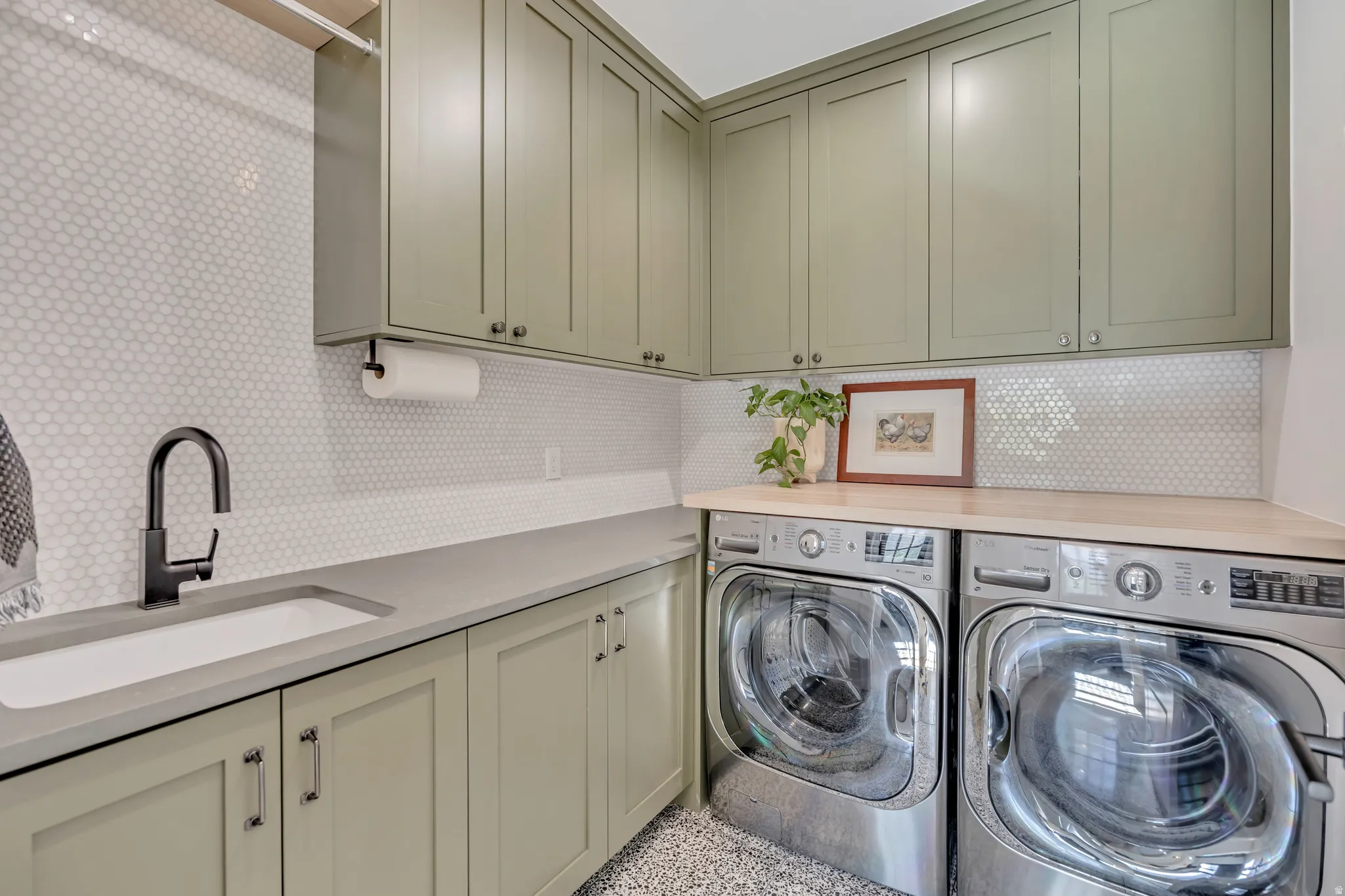 Laundry room featuring cabinet space, washing machine and clothes dryer, and dark aggregate flooring