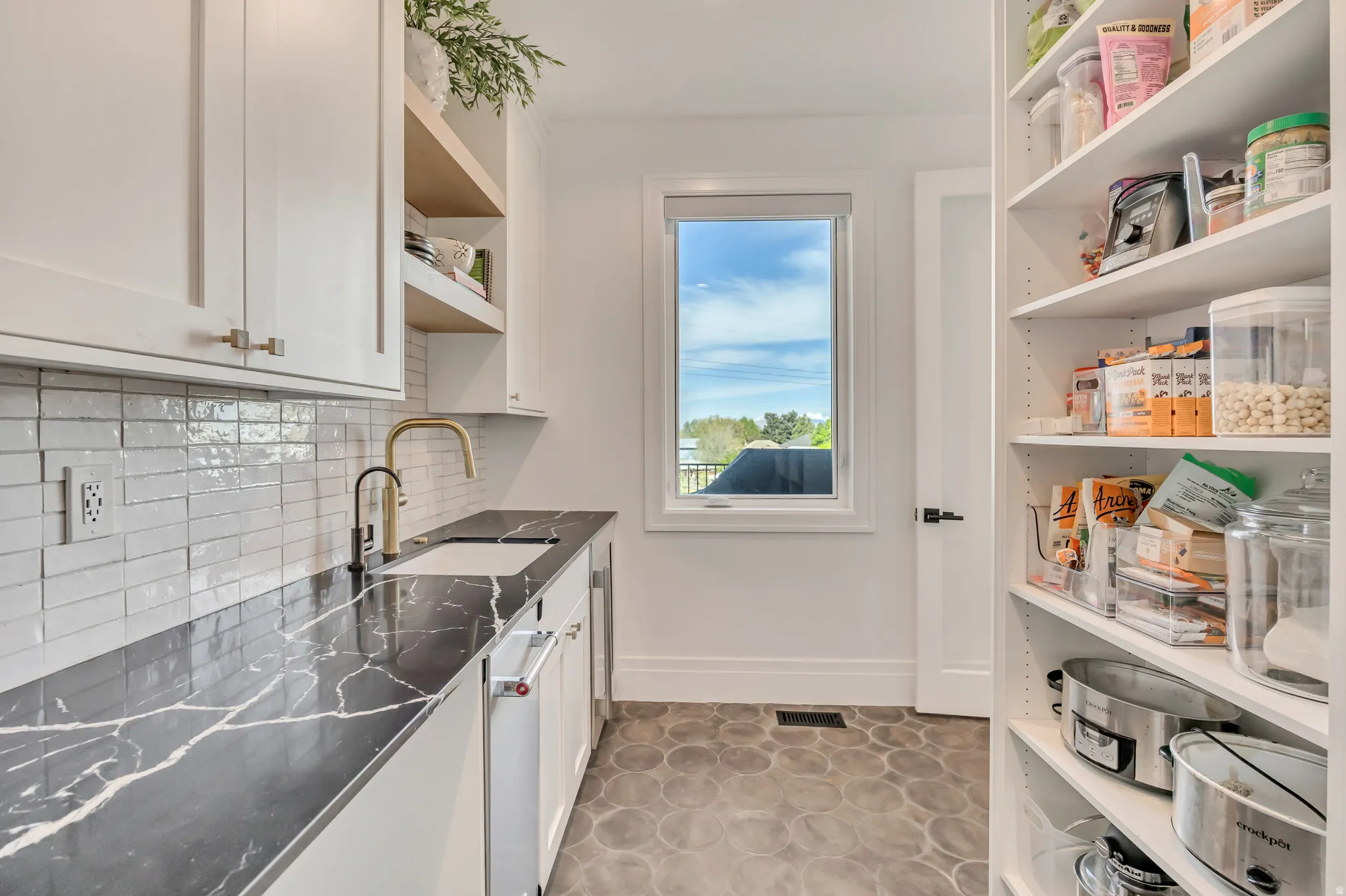 Kitchen featuring white cabinetry, dishwasher, decorative backsplash, and open shelves