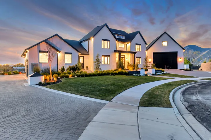 Modern farmhouse featuring decorative driveway, a garage, a lawn, and stucco siding