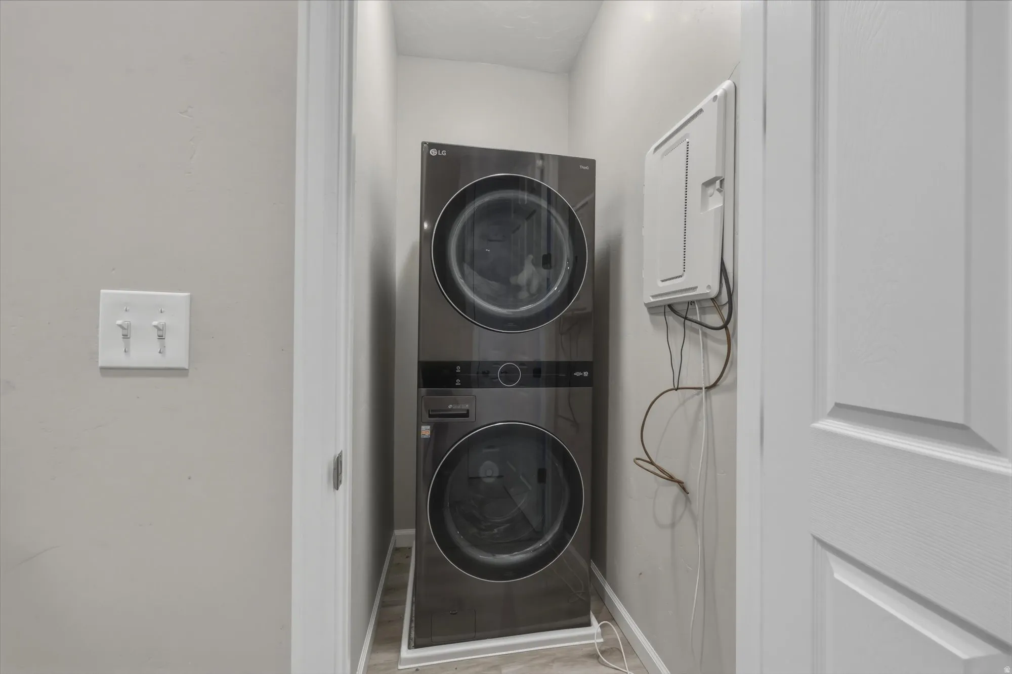 Laundry area with stacked washer / drying machine and baseboards