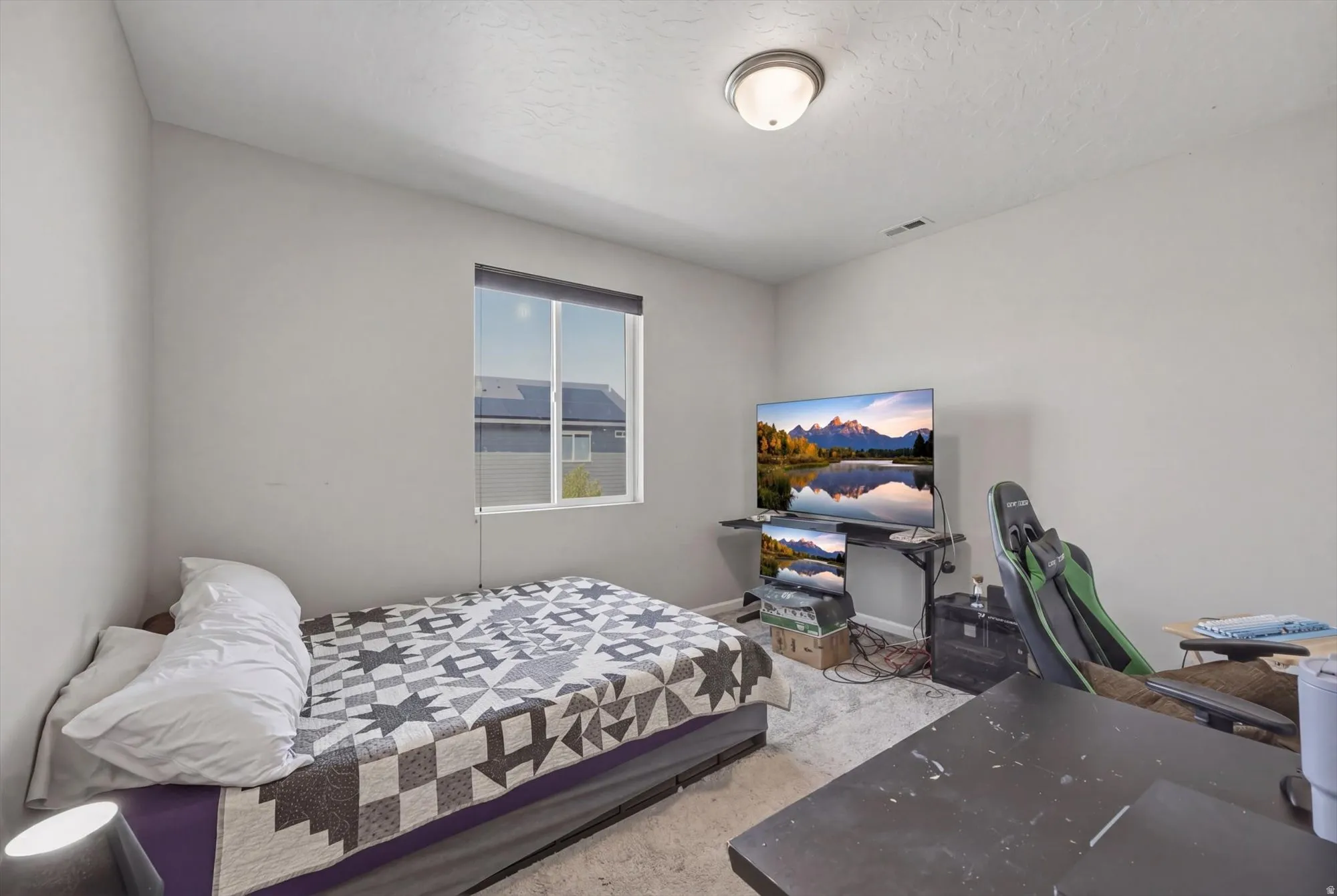 Bedroom with a textured ceiling and light carpet