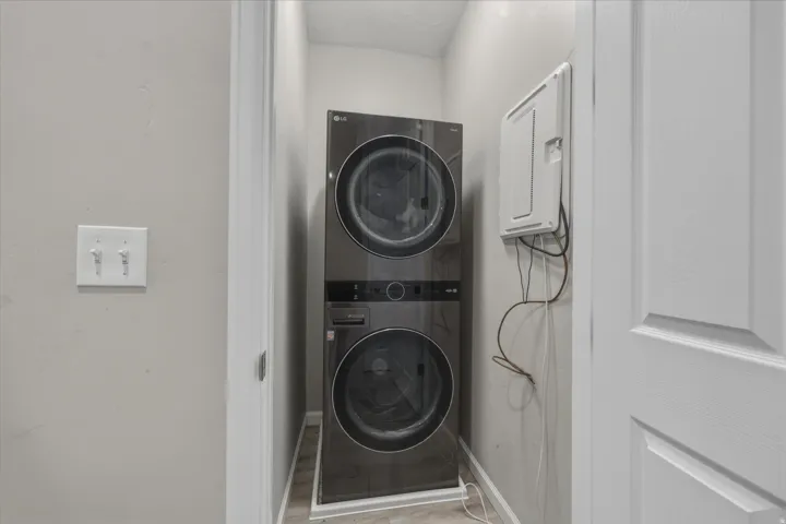 Laundry area with stacked washer / drying machine and baseboards