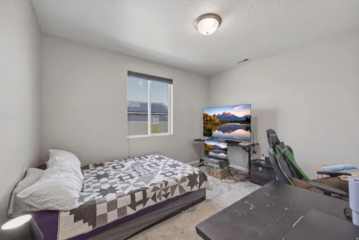 Bedroom with a textured ceiling and light carpet