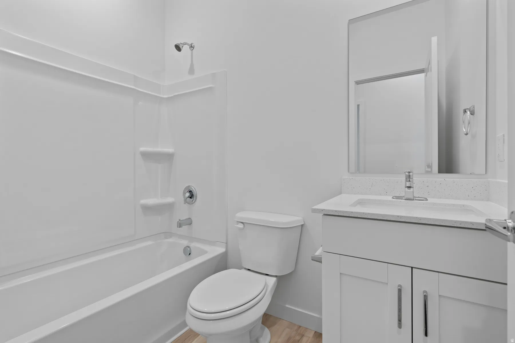 Bathroom featuring a white tub and shower surround with built-in shelving, a white toilet, and wood-finish flooring