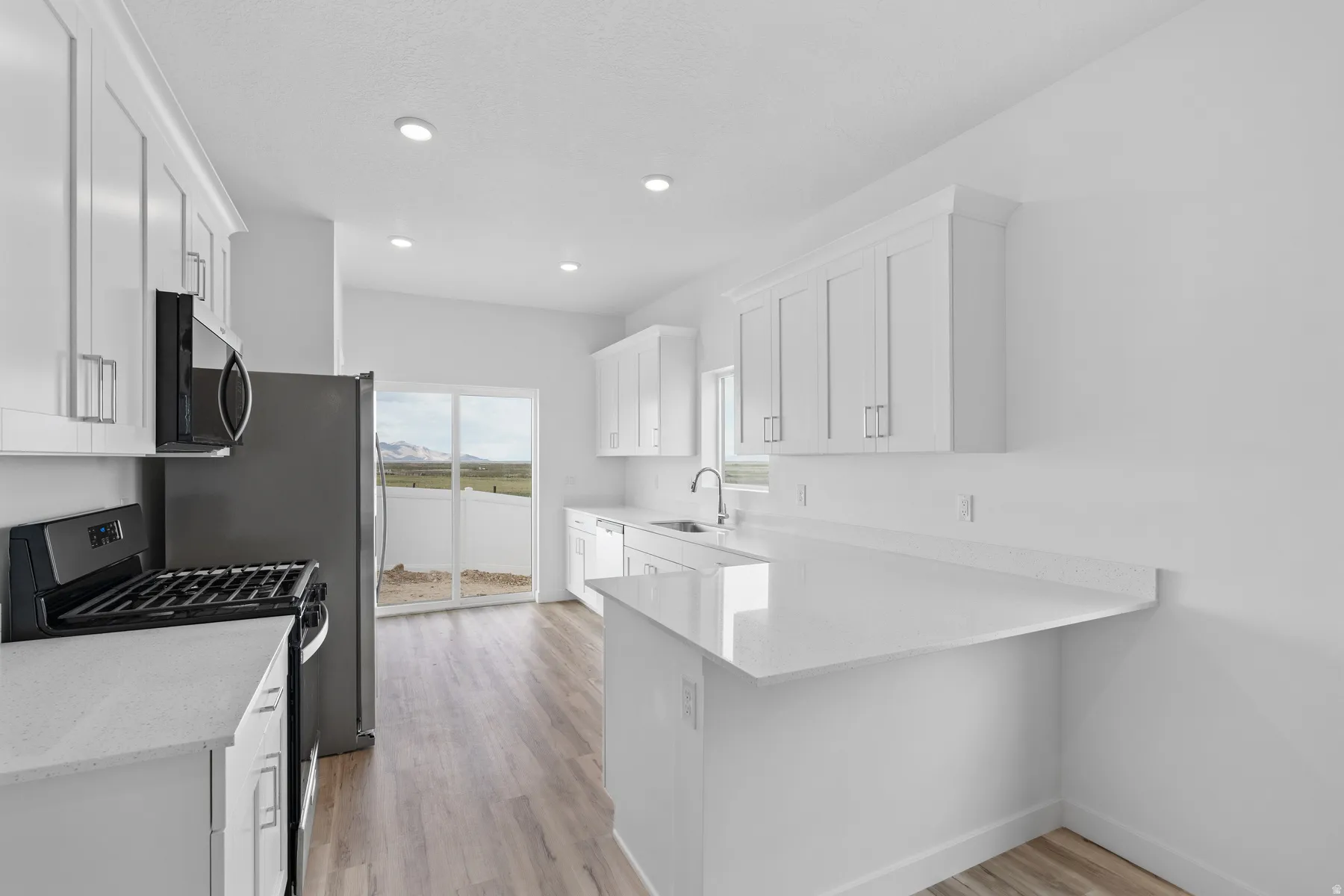 Kitchen featuring white shaker-style cabinetry, white countertops, wood-finish flooring, recessed lighting, and a sliding glass door