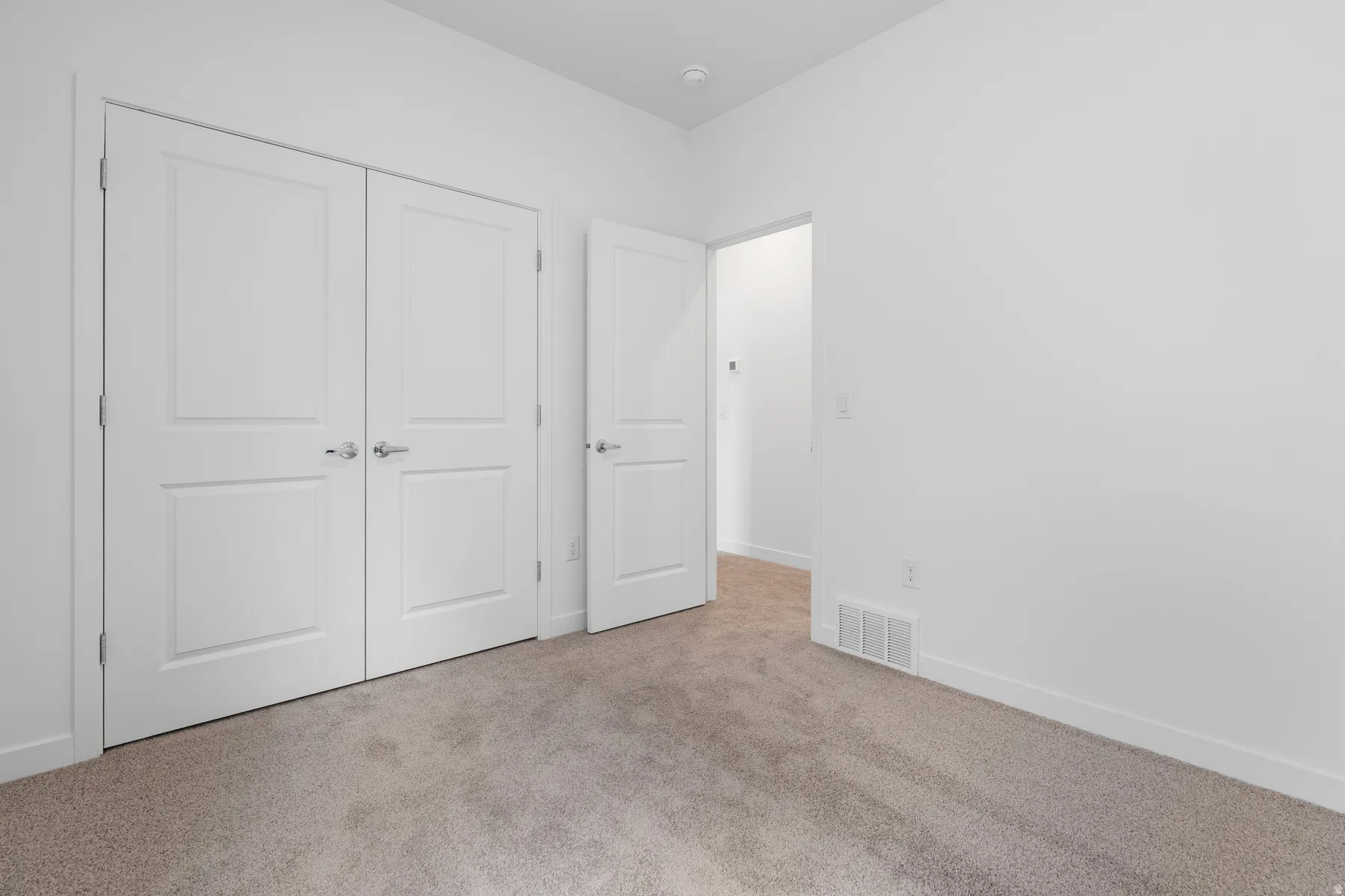 Neutral tone carpet flooring with white baseboards