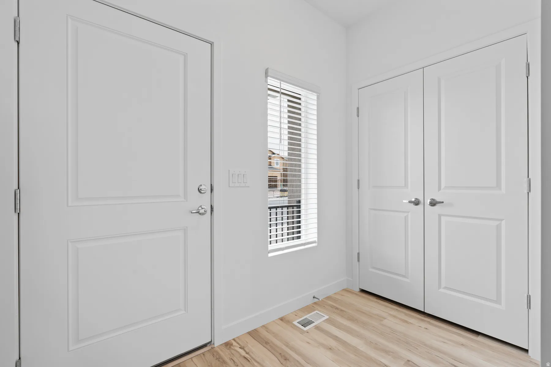 Entryway featuring wood-finish flooring and a white paneled door with brushed nickel hardware