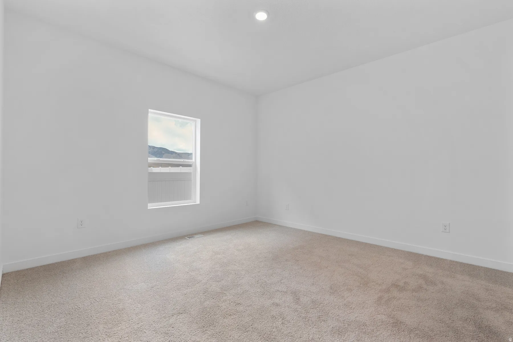 Room featuring light-toned carpeting, white walls, and a recessed ceiling light
