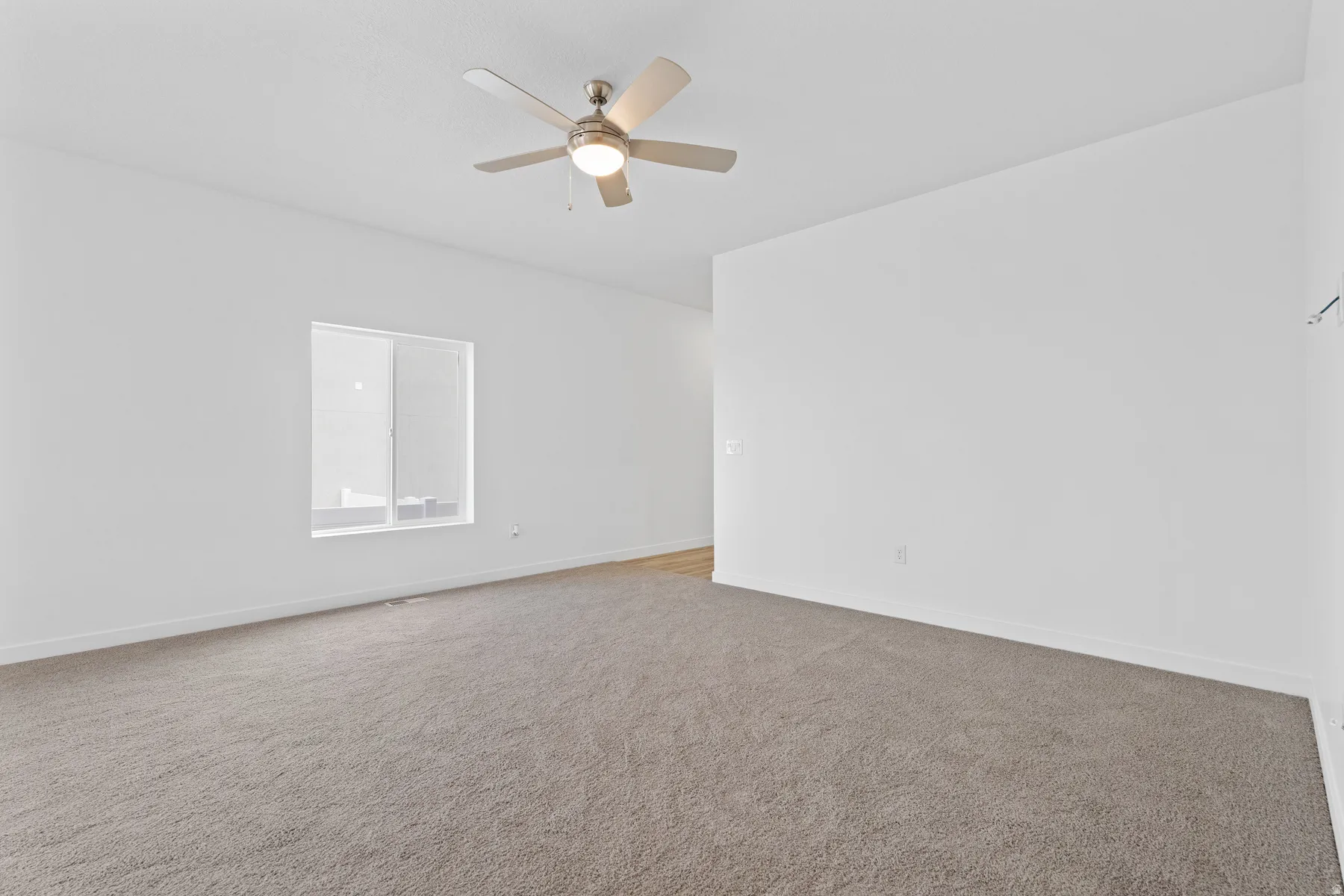 Spacious room featuring neutral carpeting and white painted walls