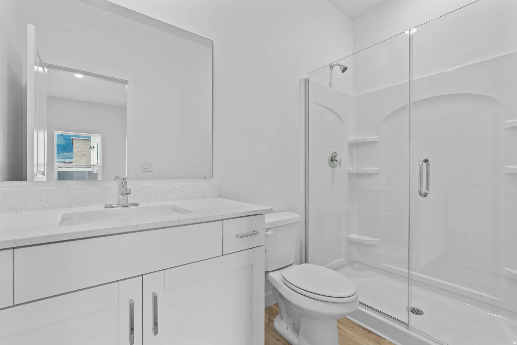Bathroom featuring a glass-enclosed shower, white vanity with an integrated sink, polished chrome faucet, and a large wall-mounted mirror