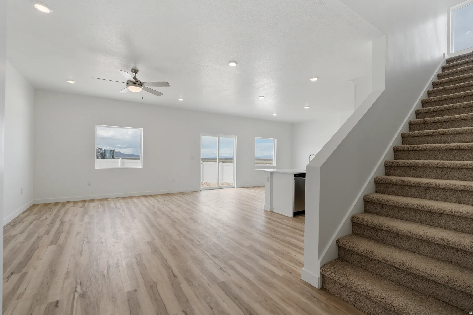 Open-concept living area featuring wood-finish flooring, a contemporary ceiling fan, and recessed lighting