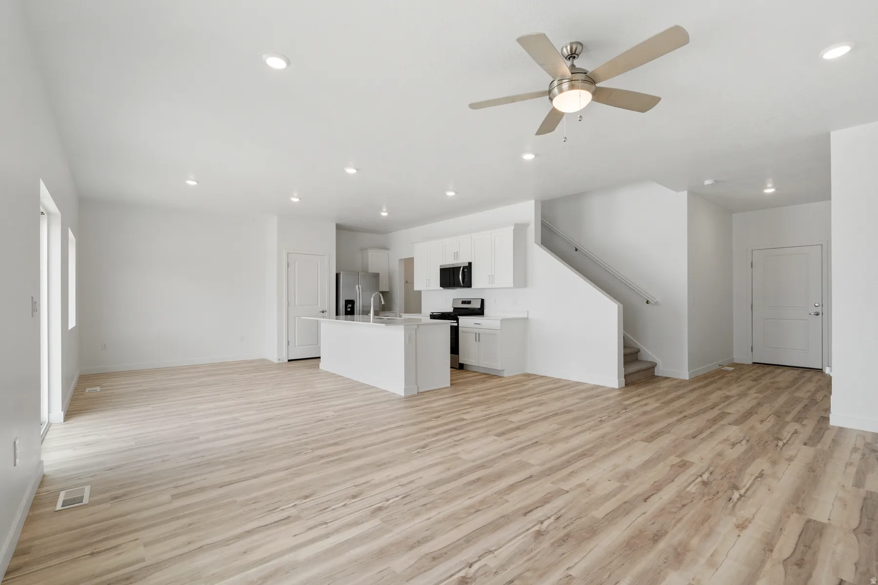 Open-concept living space featuring wood-finish flooring, recessed lighting, and a modern ceiling fan