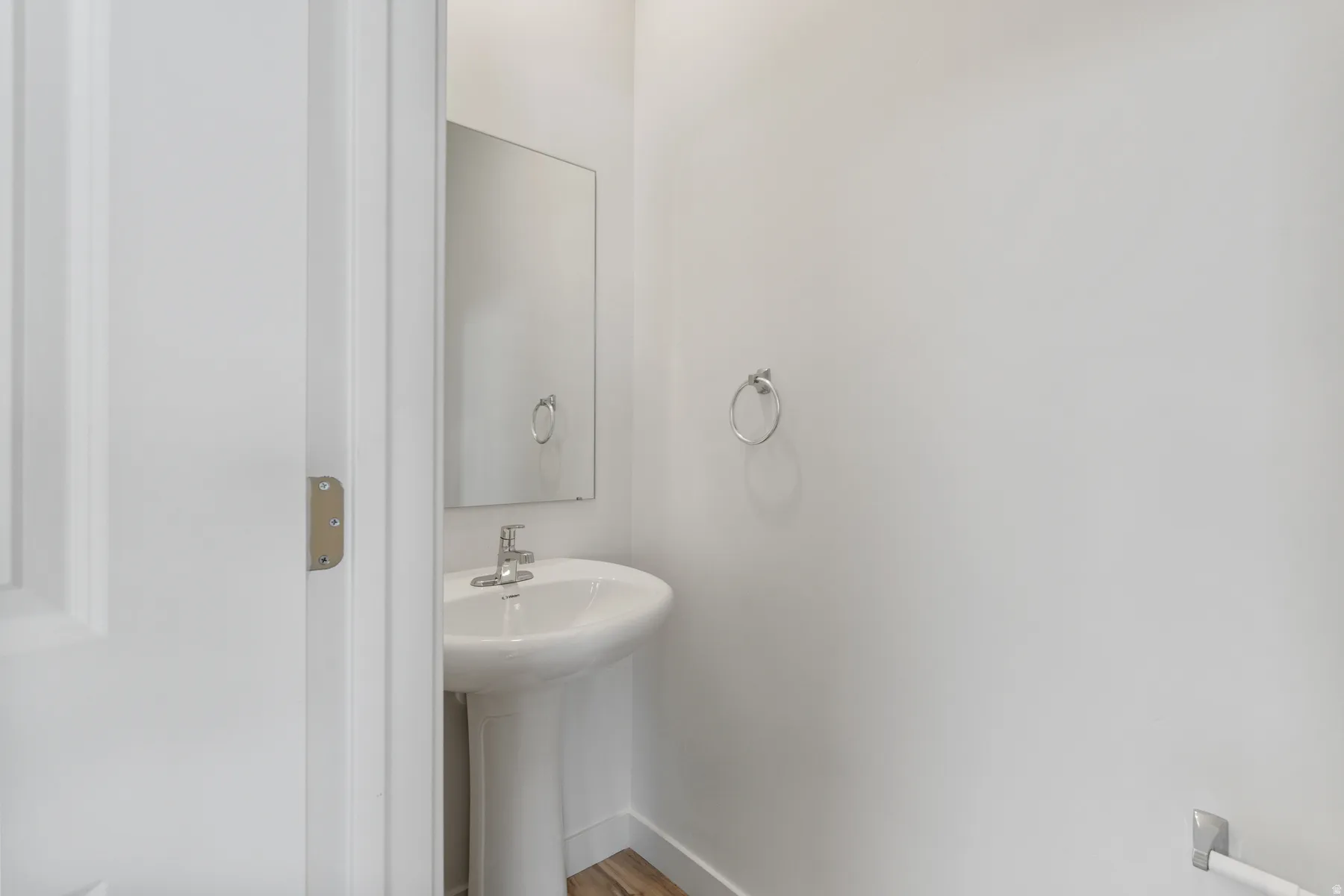 Pedestal sink with chrome faucet, complemented by a rectangular wall-mounted mirror