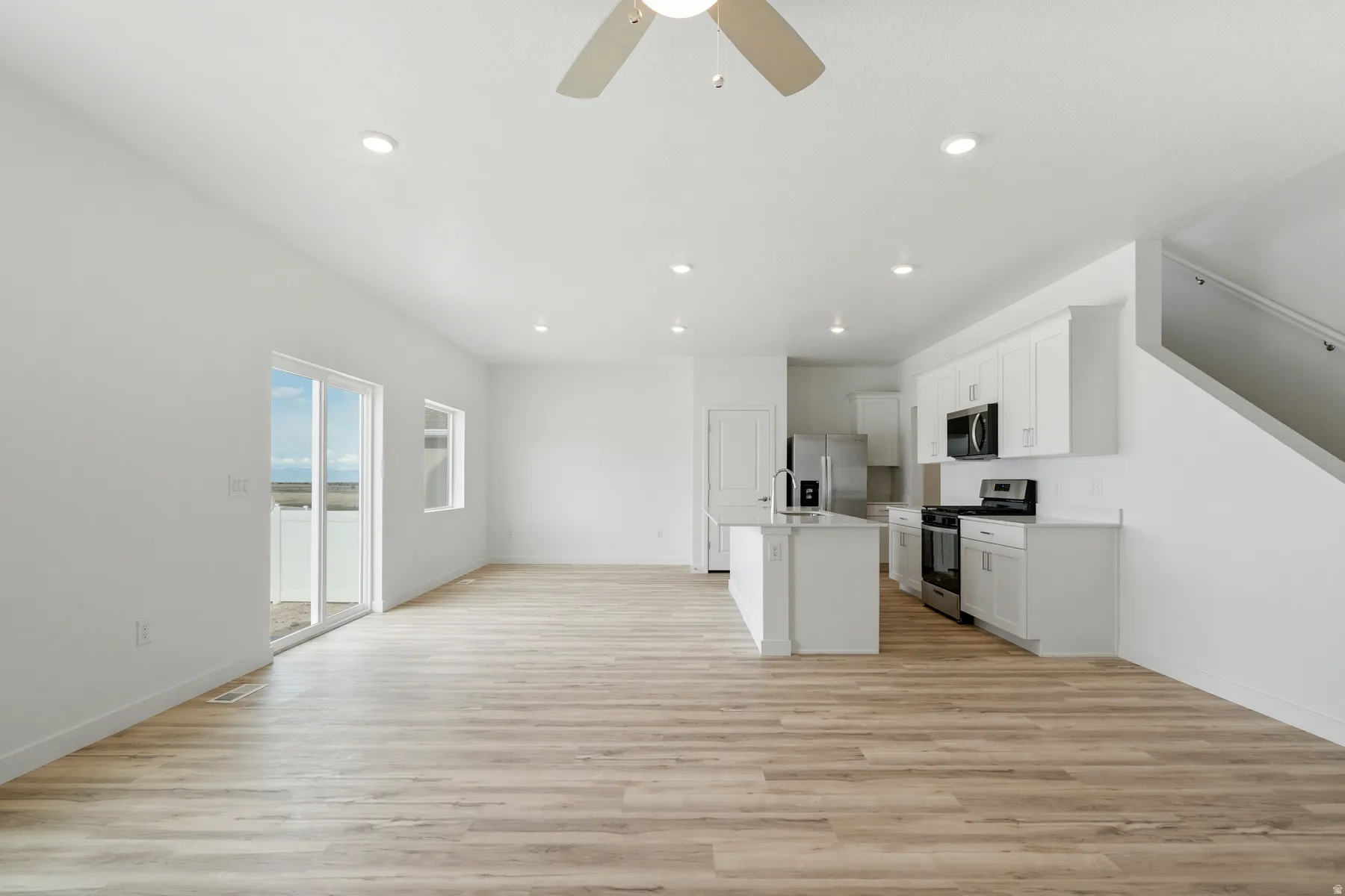 Open-concept living space featuring wood-finish flooring, recessed lighting, and a modern ceiling fan