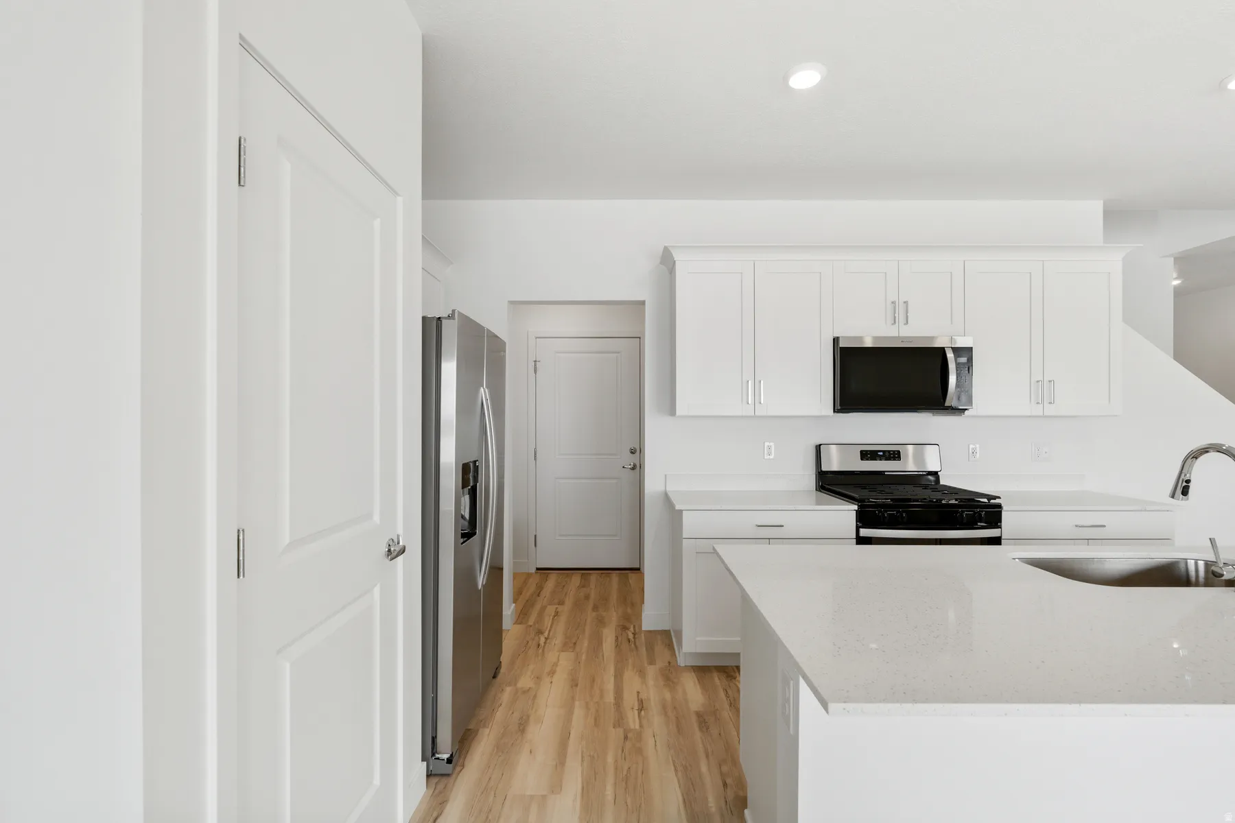 Contemporary kitchen featuring white cabinetry, light-toned countertops, and wood-finish flooring