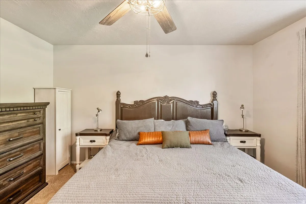 Bedroom with carpet, ceiling fan, and a textured ceiling