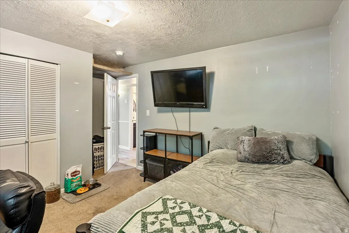 Bedroom featuring carpet floors, a closet, and a textured ceiling