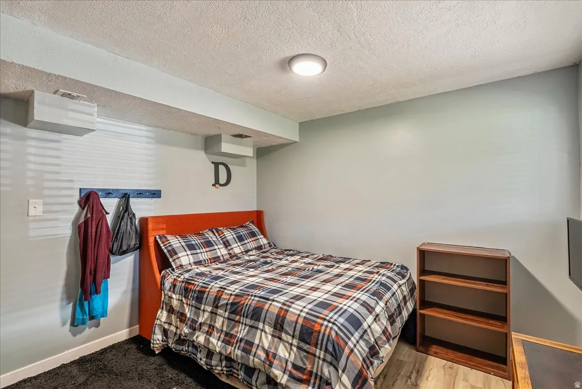 Bedroom with a textured ceiling and wood finished floors