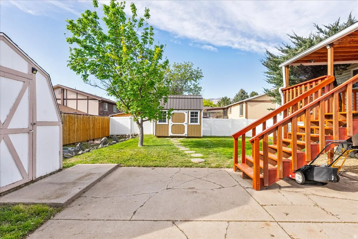 Fenced backyard featuring a storage shed and a patio area