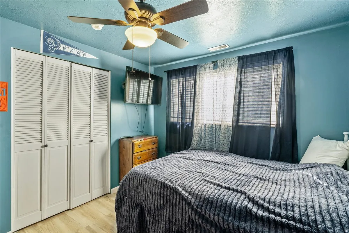 Bedroom featuring a textured ceiling, wood finished floors, a closet, and ceiling fan