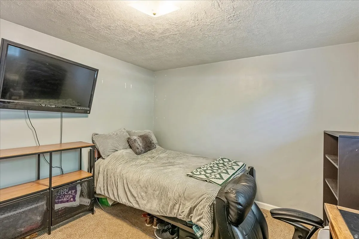 Bedroom with light carpet and a textured ceiling