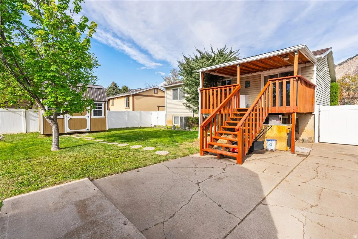 Back of property with a storage shed, a fenced backyard, a patio, a gate, and a deck
