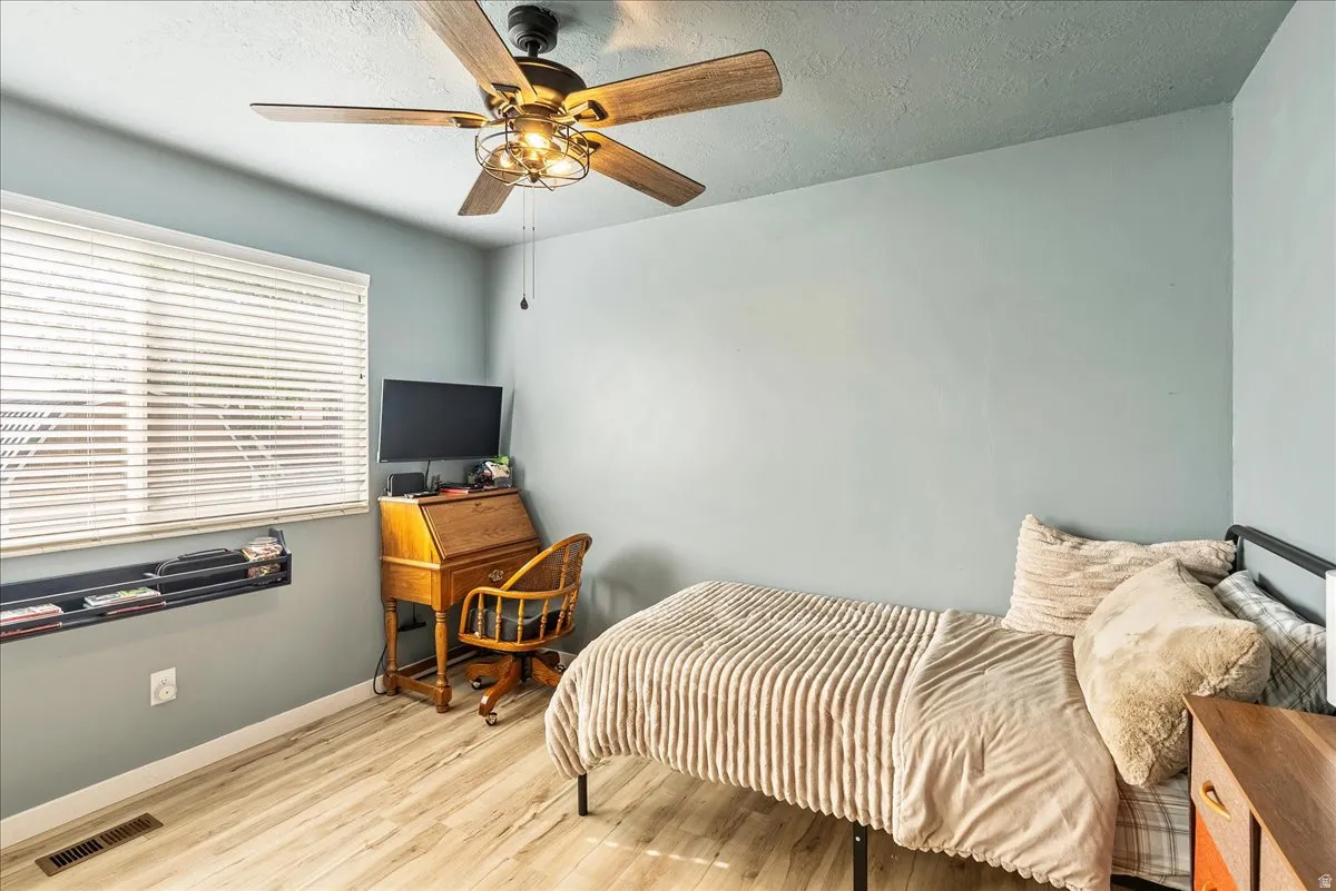Bedroom featuring light wood-style flooring, a textured ceiling, and a ceiling fan