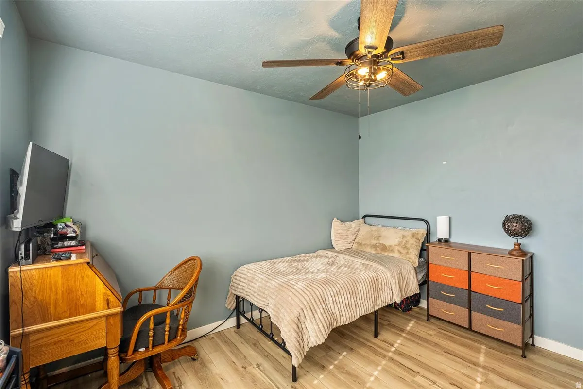 Bedroom featuring light wood-style floors, a ceiling fan, and a textured ceiling