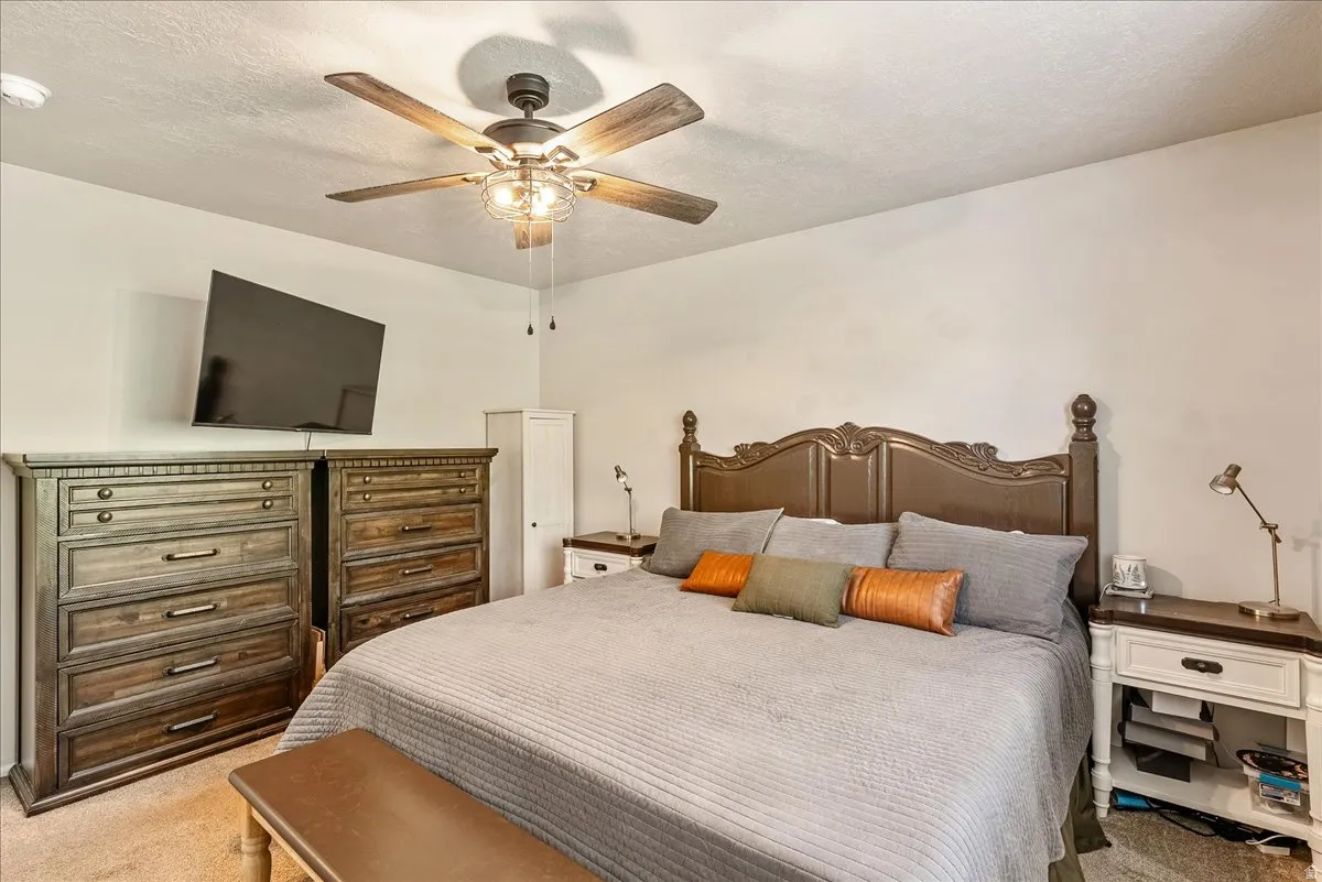 Bedroom featuring carpet floors, a textured ceiling, and ceiling fan