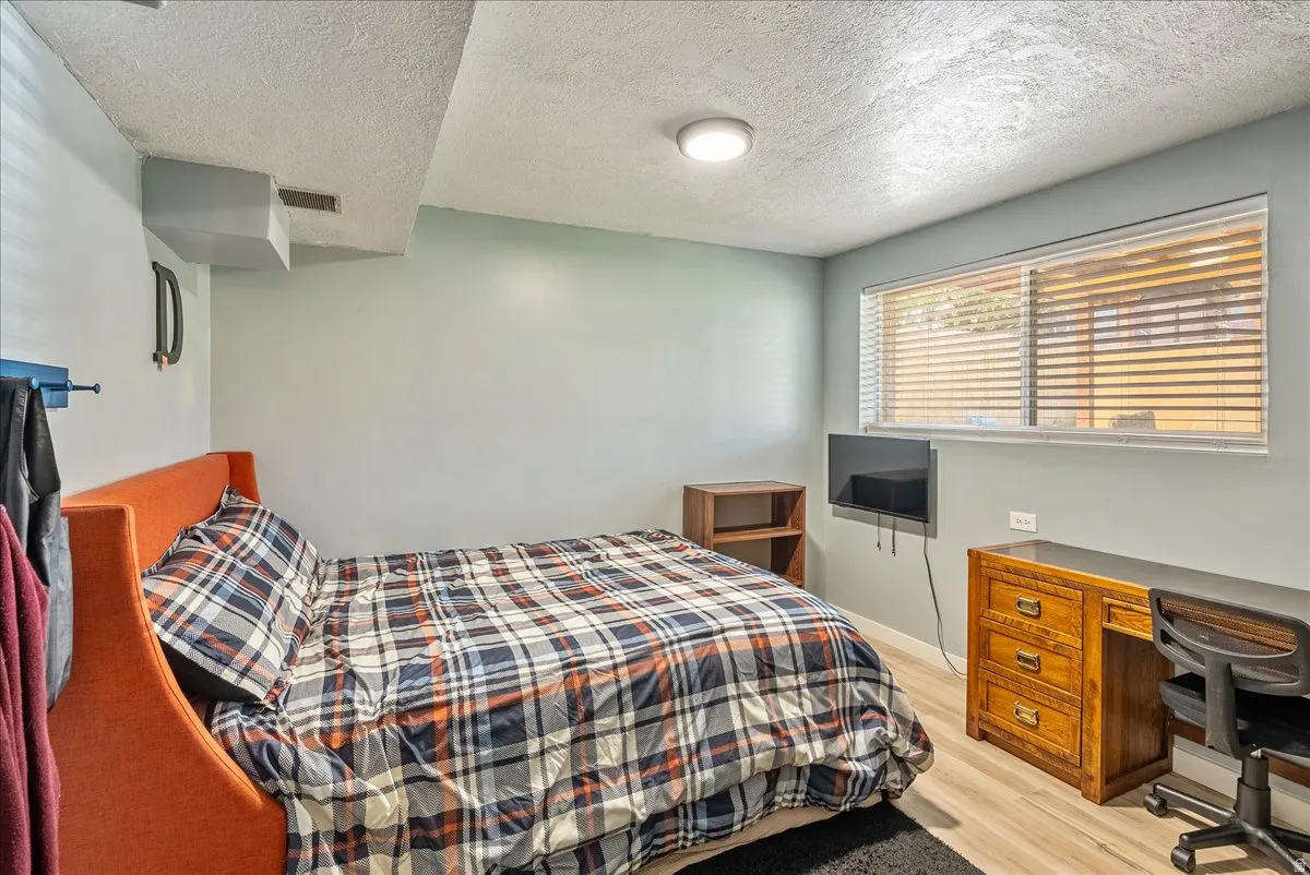 Bedroom with a desk, a textured ceiling, and light wood-style flooring