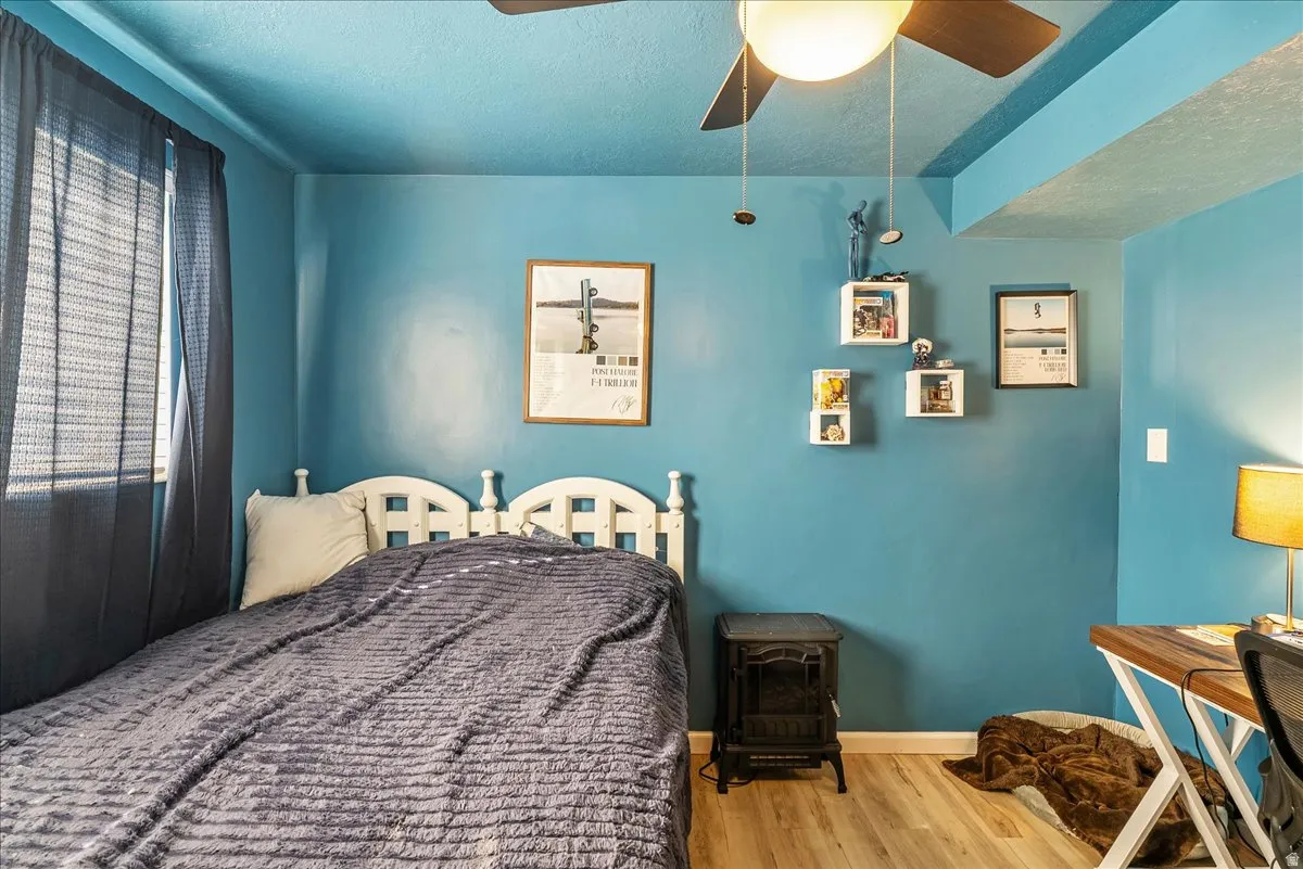 Bedroom with a textured ceiling, wood finished floors, and ceiling fan