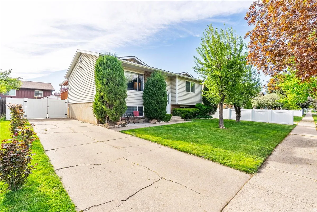 Raised ranch featuring a gate, concrete driveway, and a patio