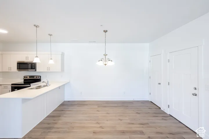 Kitchen featuring white cabinetry, stainless steel microwave, and pendant lighting