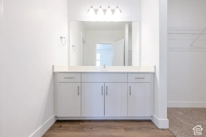White vanity with a single basin sink and light-toned countertop