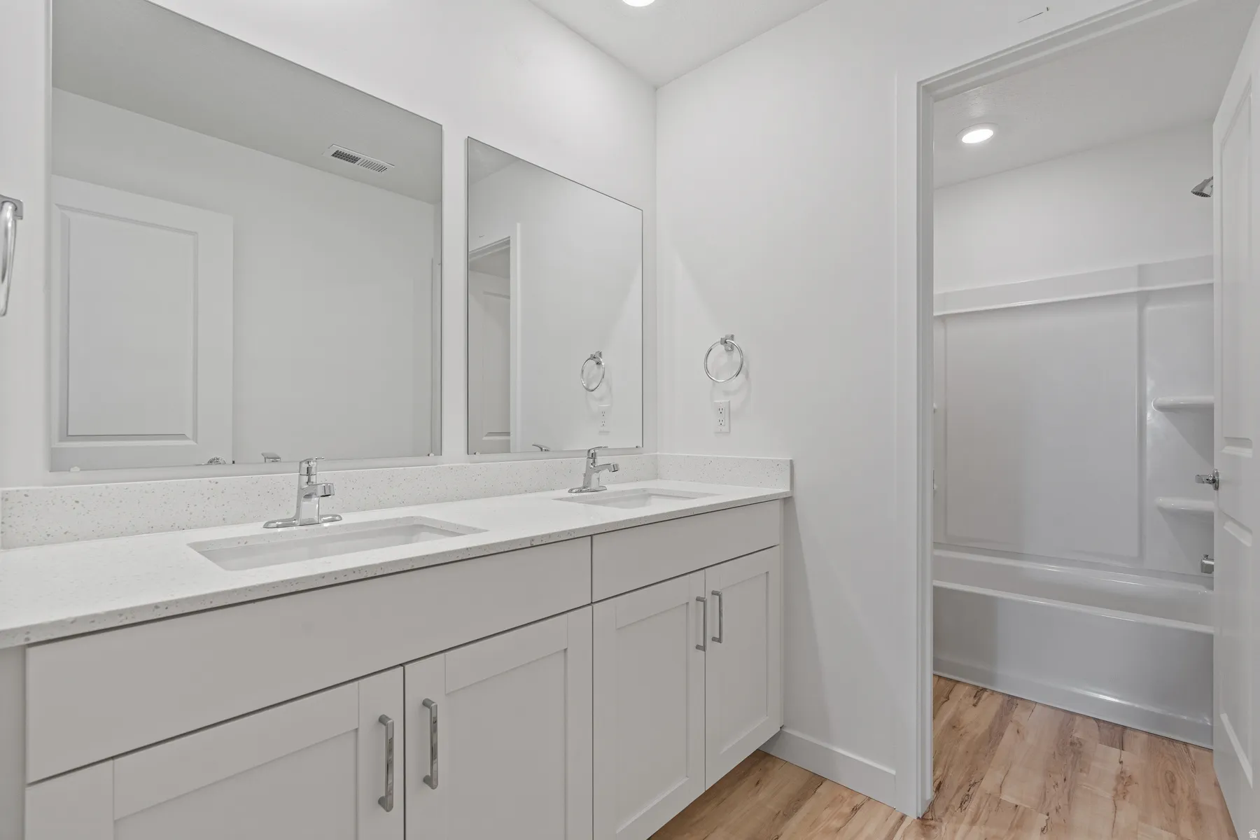 White vanity with dual integrated sinks, light-toned countertop, and two mirrors