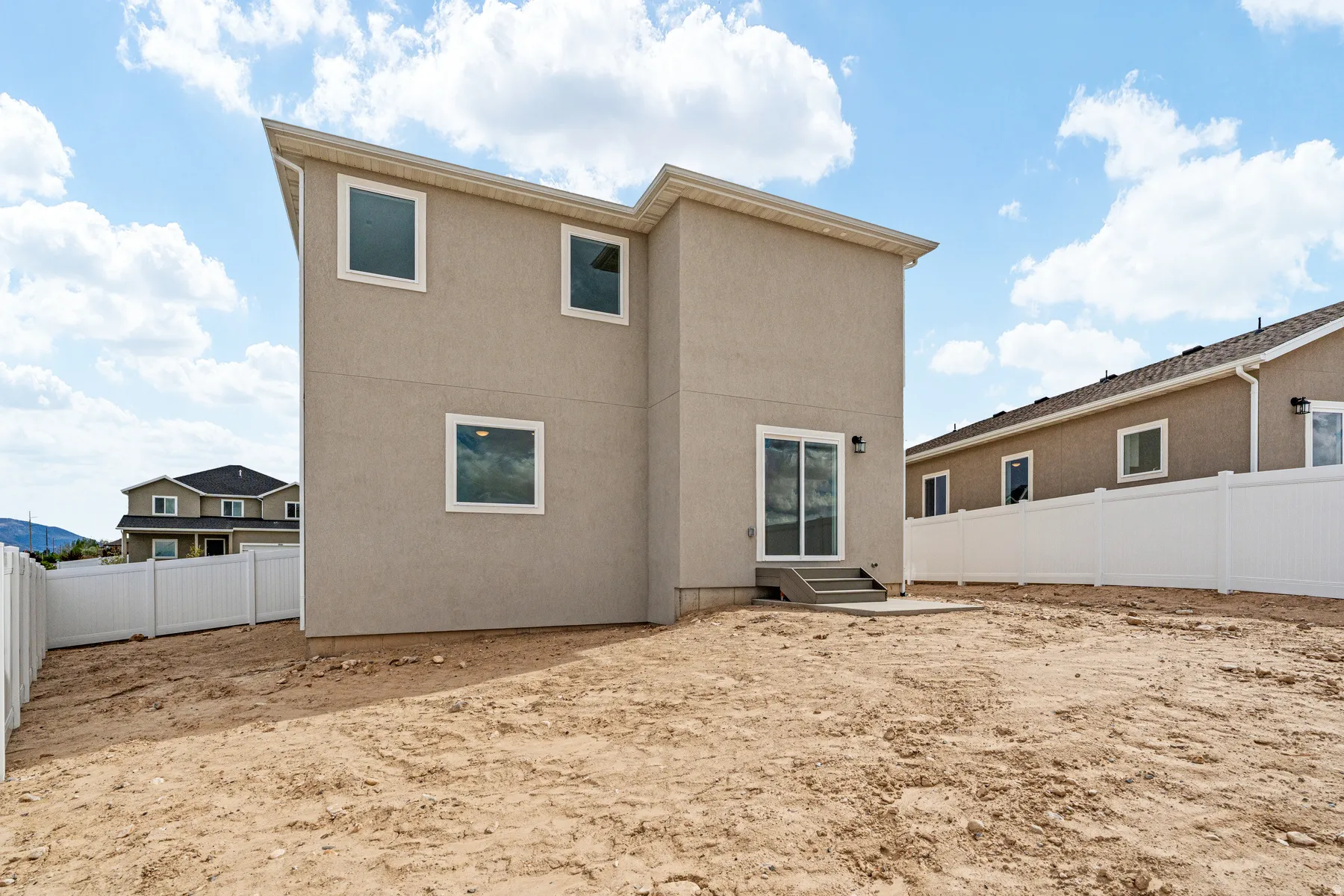 Stucco exterior featuring multiple windows and a sliding glass door