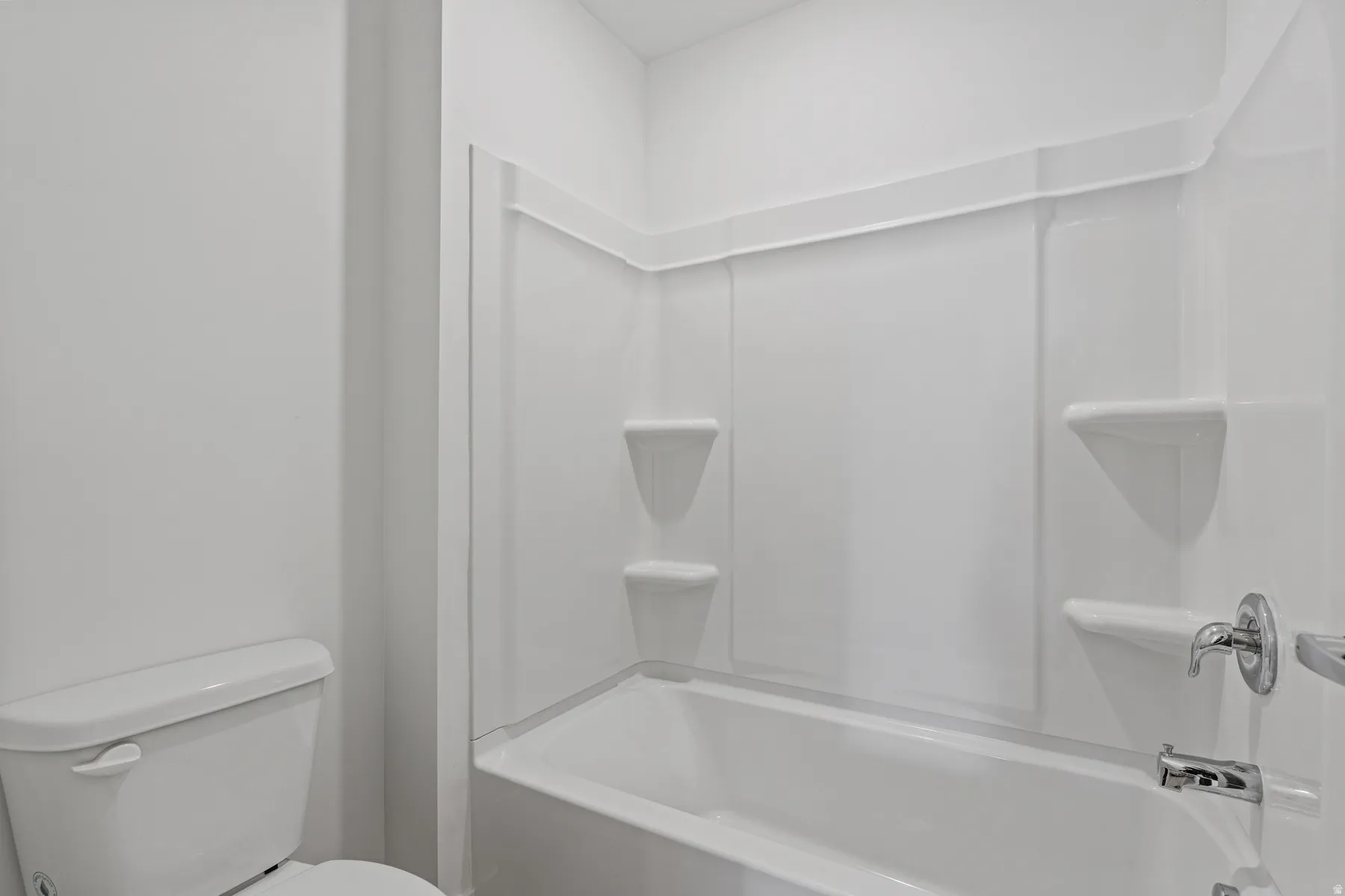White bathtub and shower combination unit featuring integrated shelving