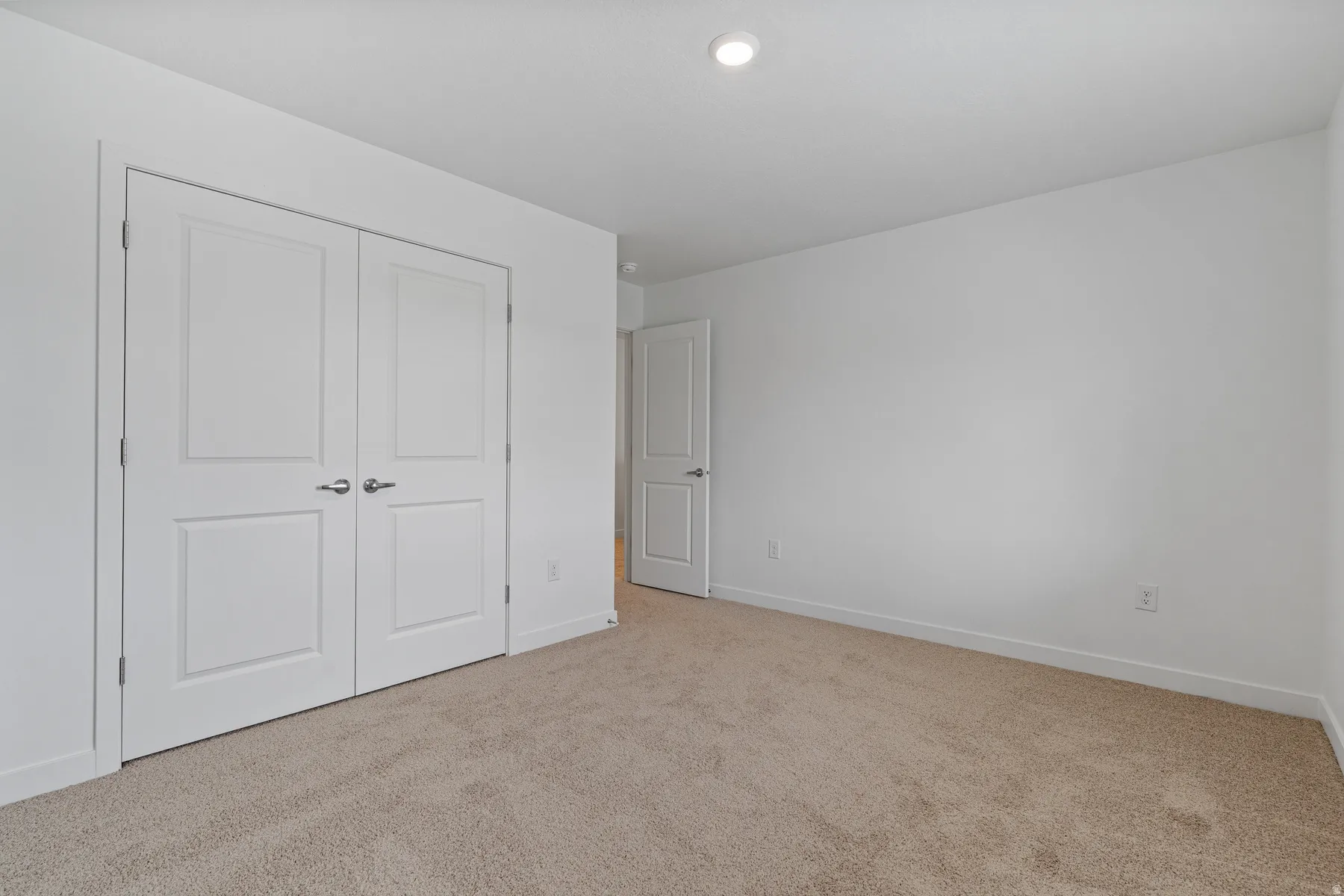 Expansive room featuring light-colored carpeting and white walls
