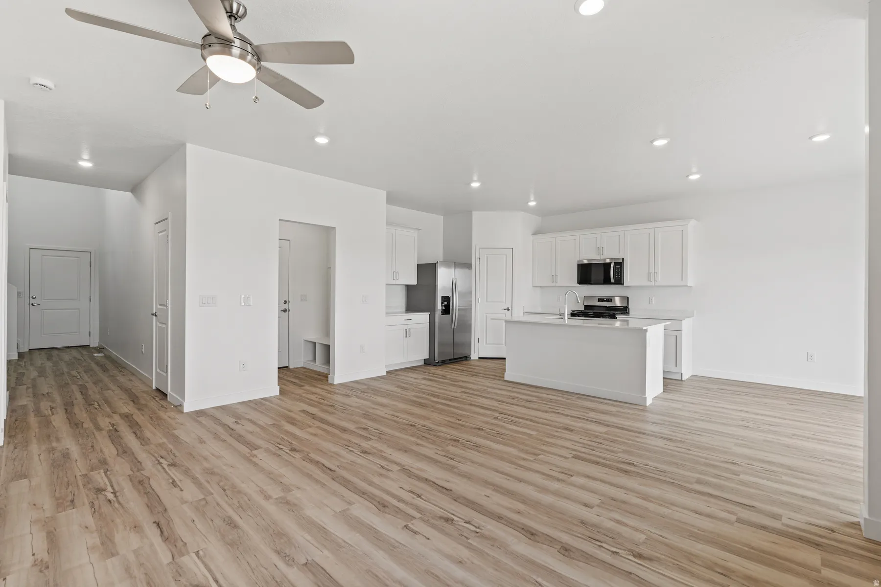 Open-concept living area with wood-finish flooring, recessed lighting, and a contemporary ceiling fan