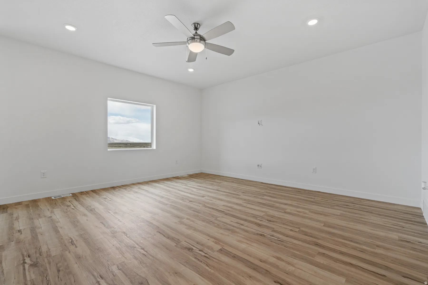 Spacious room featuring wood-finish flooring, recessed lighting, and a contemporary ceiling fan