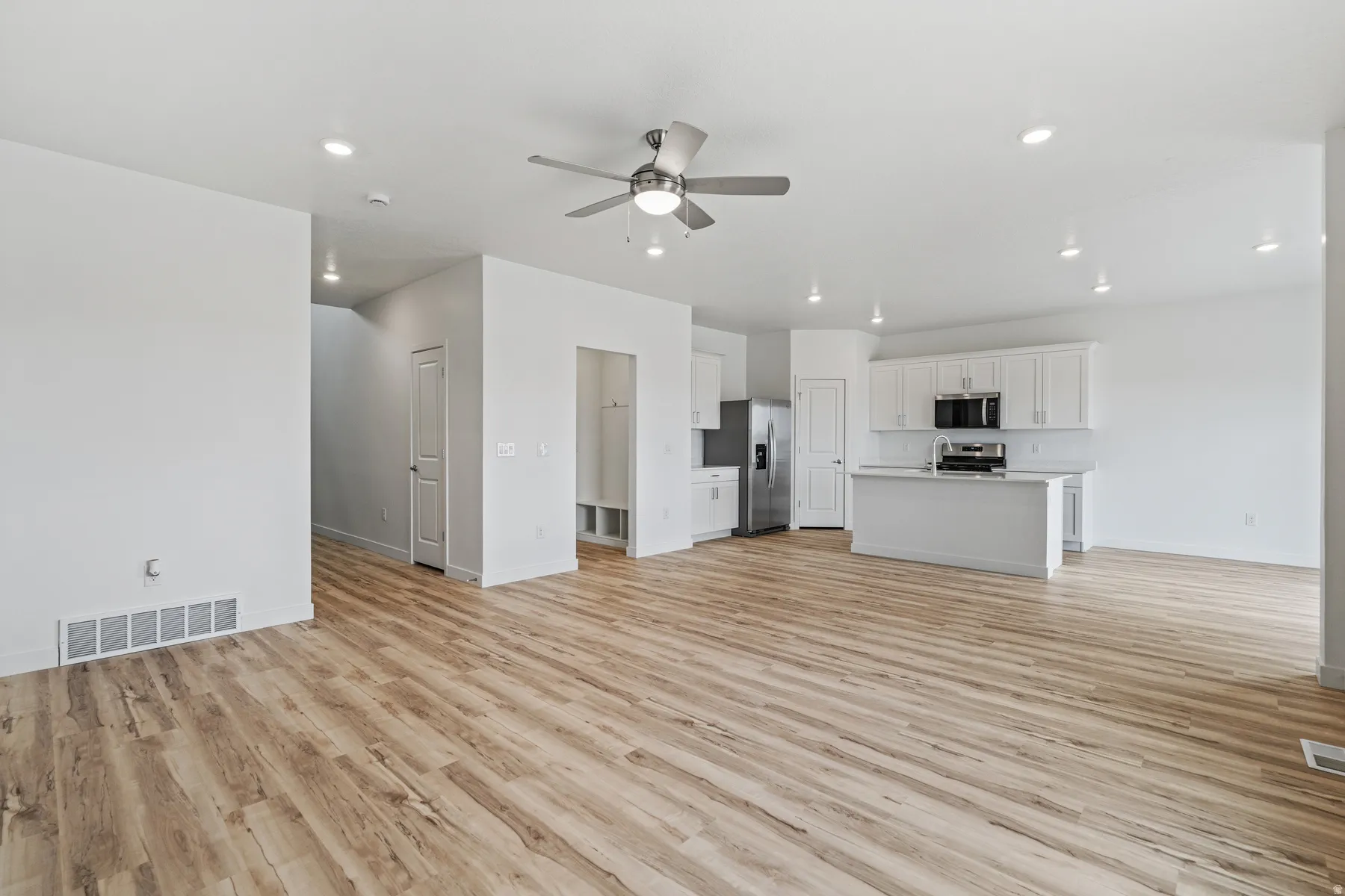 Open-concept living area featuring wood-finish flooring, recessed lighting, and a ceiling fan