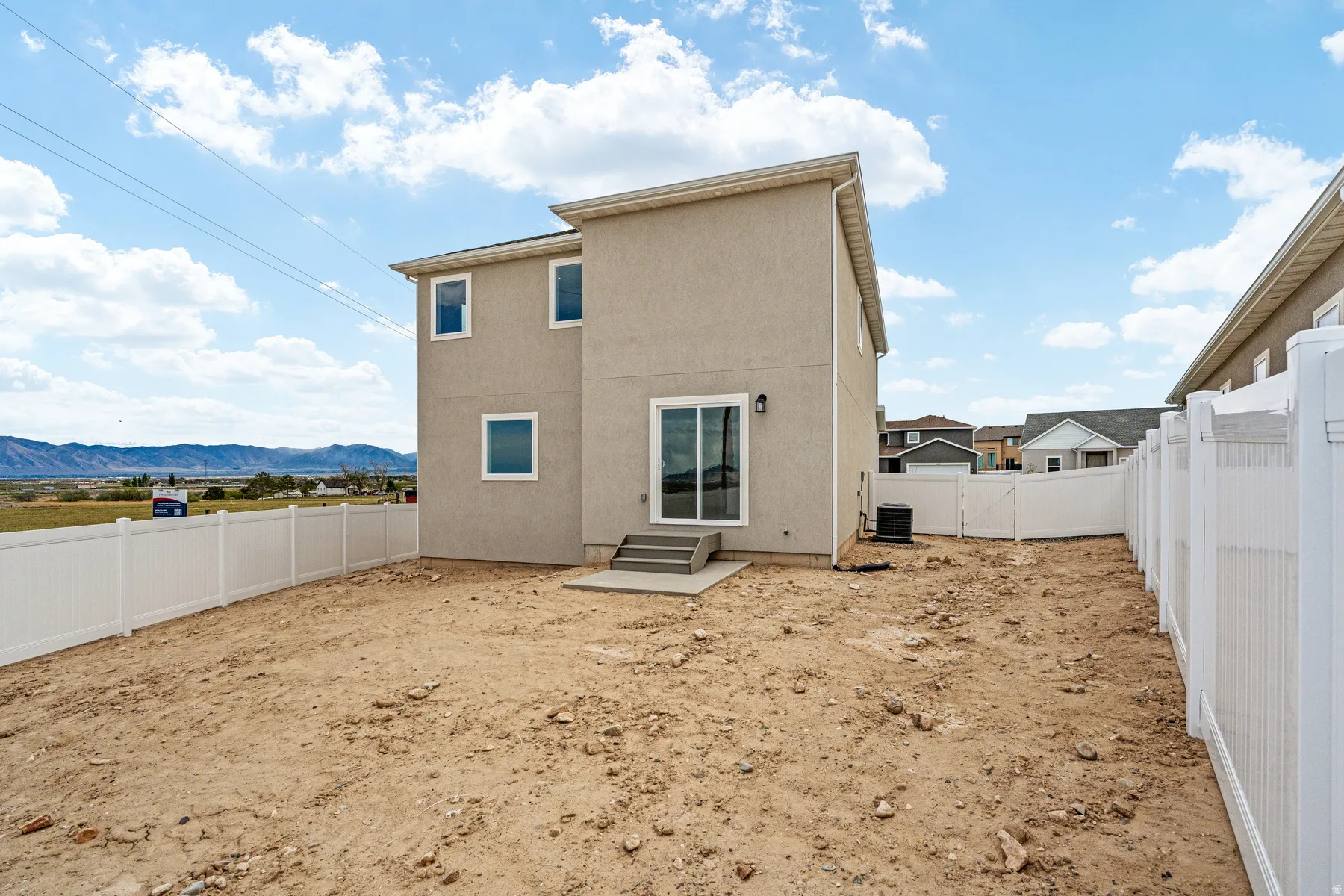 Rear exterior with a concrete patio, sliding glass door, and multiple windows