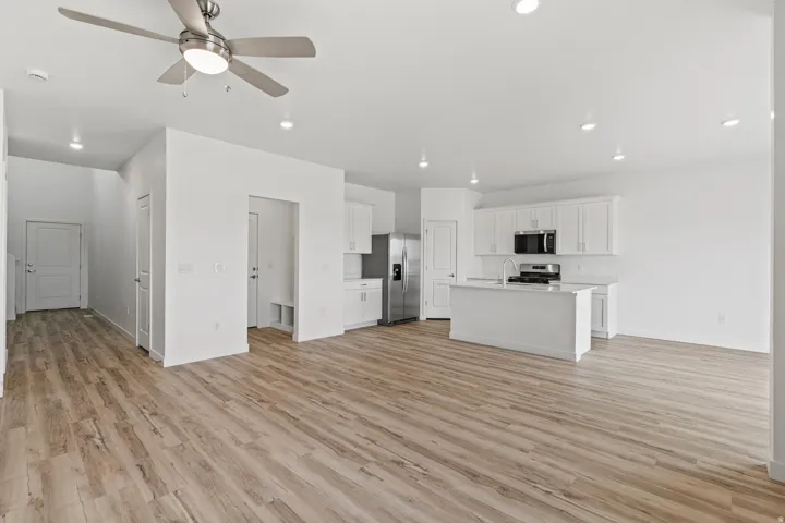 Open-concept living area with wood-finish flooring, recessed lighting, and a contemporary ceiling fan