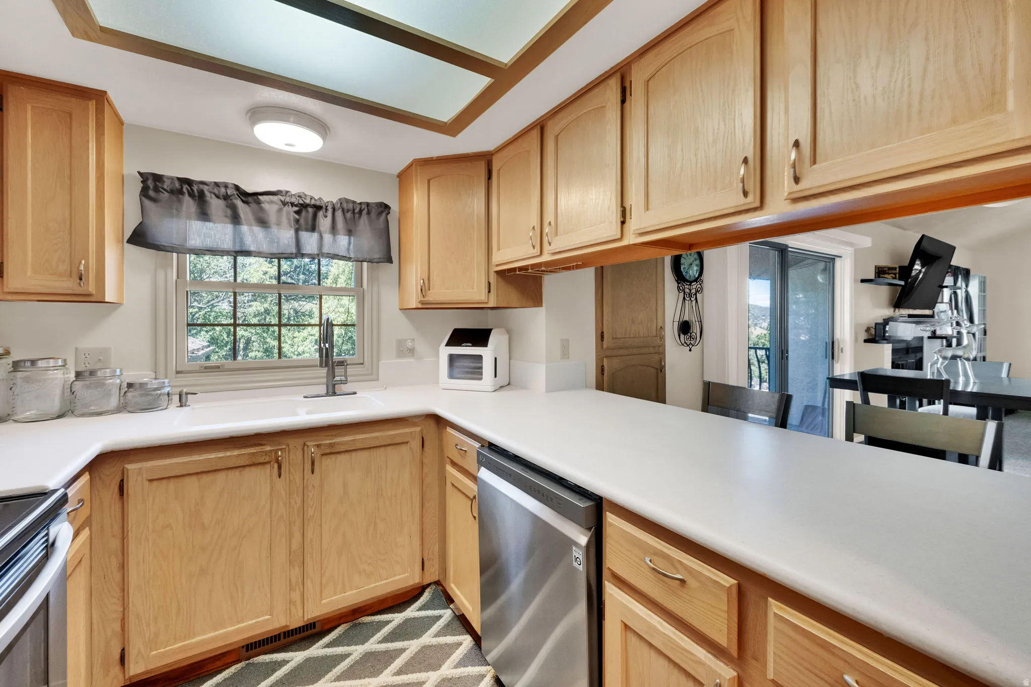 Kitchen featuring stainless steel appliances, light countertops, and light wood finish cabinets