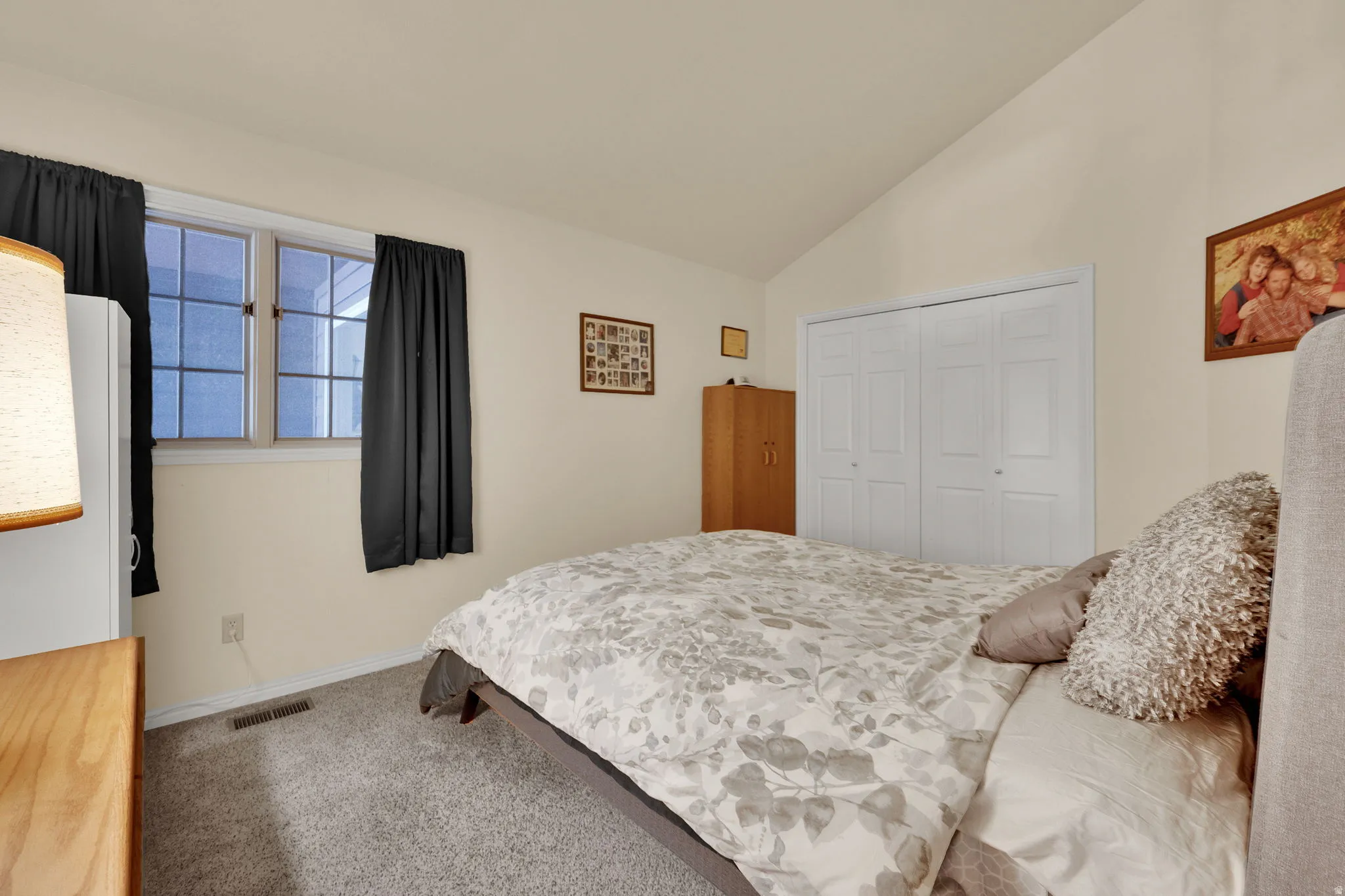 Bedroom featuring light colored carpet, lofted ceiling, and a closet