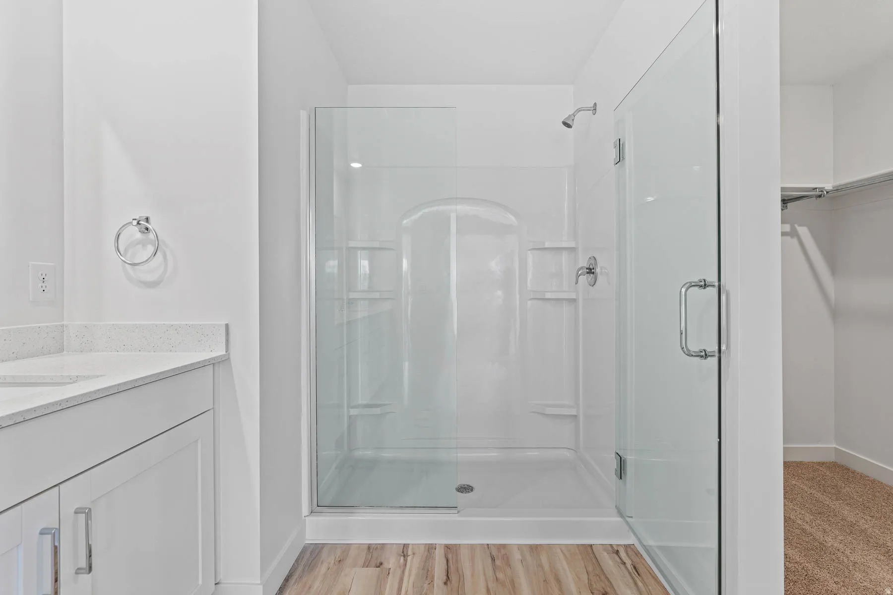 Walk-in shower with clear glass enclosure and integrated shelving