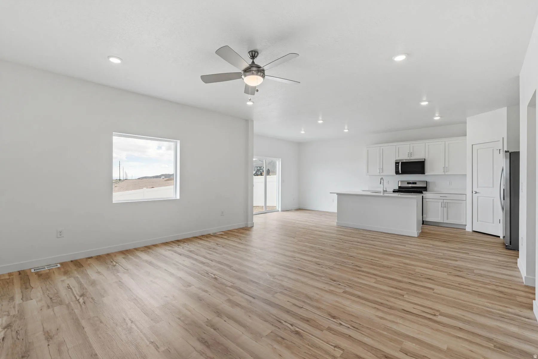Open-concept living space featuring wood-finish flooring, recessed lighting, and a modern ceiling fan