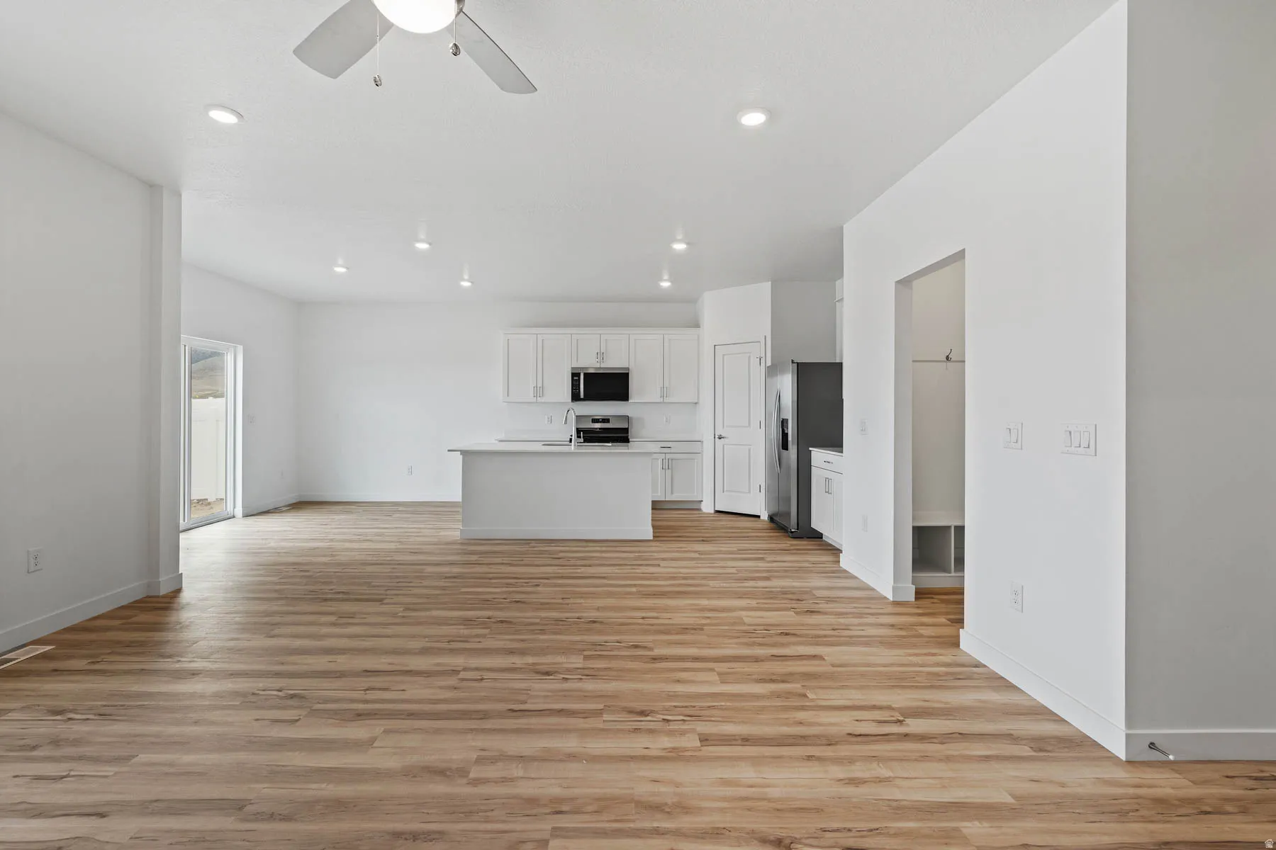 Expansive open-concept room featuring wood-finish flooring, recessed lighting, and a contemporary ceiling fan