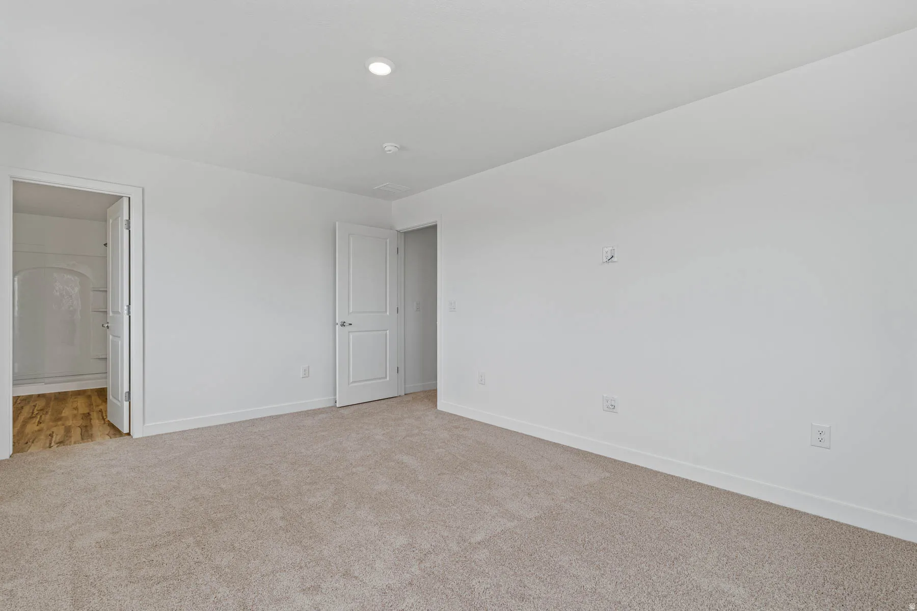 Spacious room featuring neutral carpeting, white painted walls, recessed lighting, and white trim