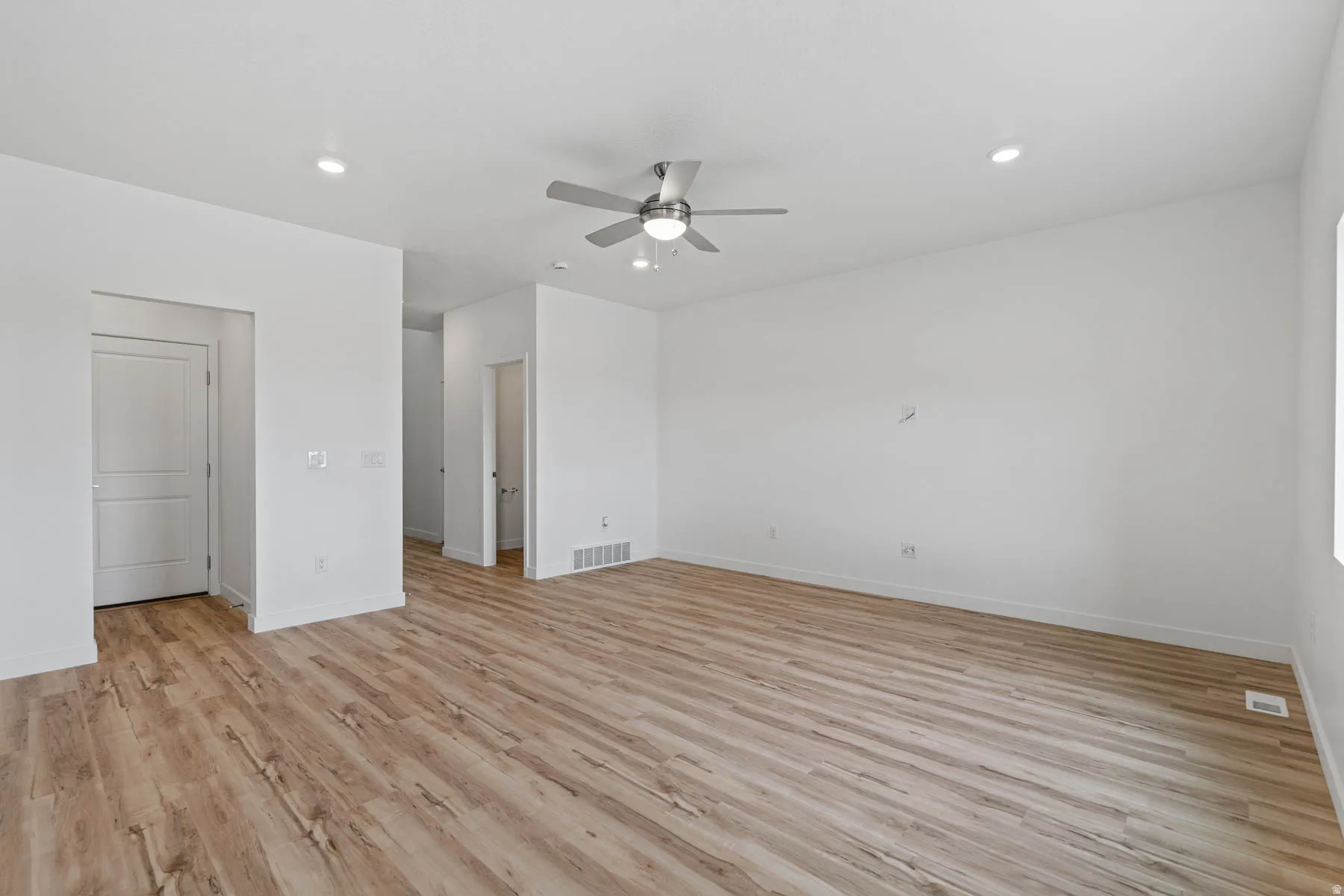 Spacious room featuring wood-finish flooring, recessed lighting, and a modern ceiling fan